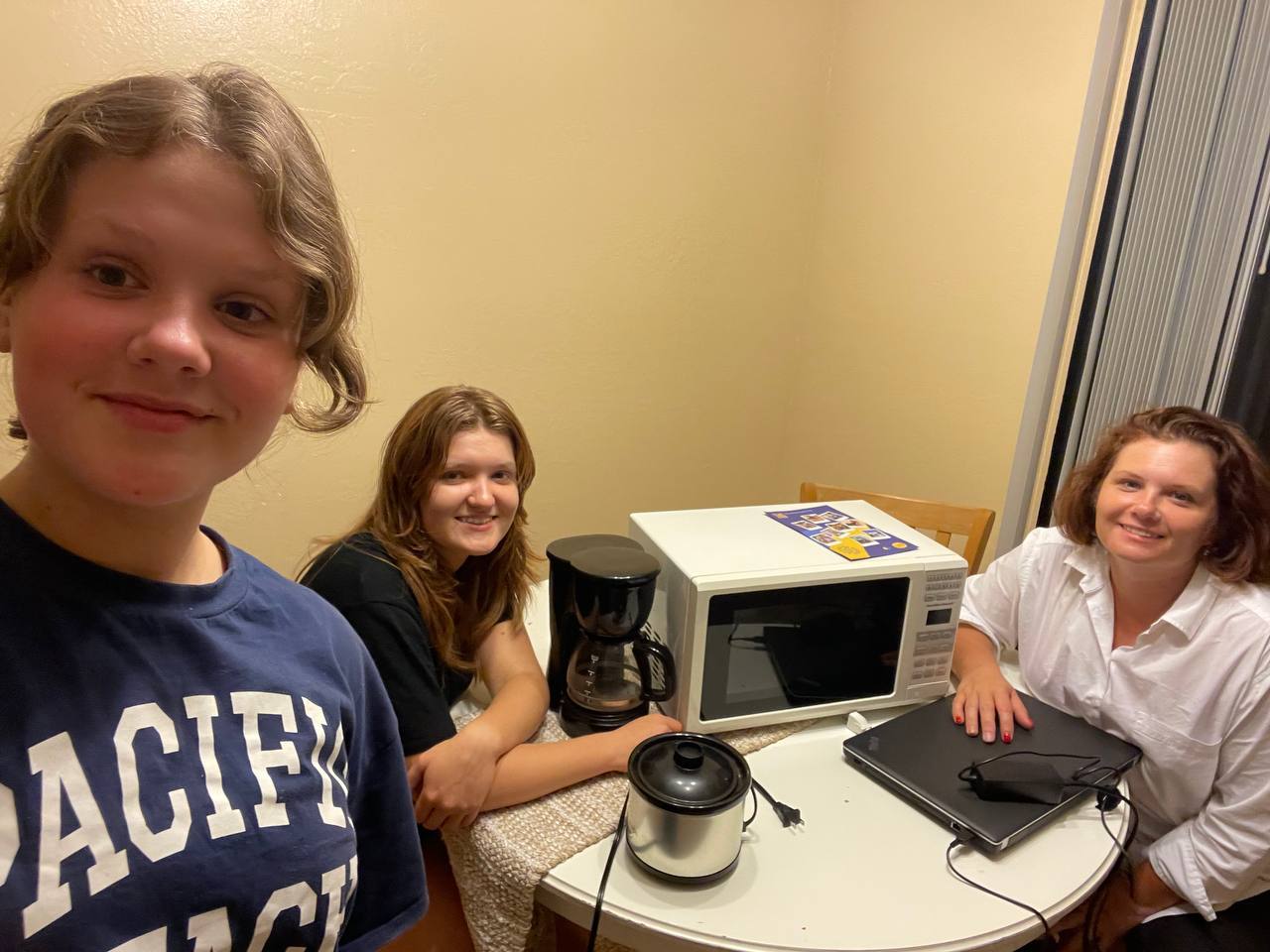 Three women smile and pose in a bright, modern office setting.