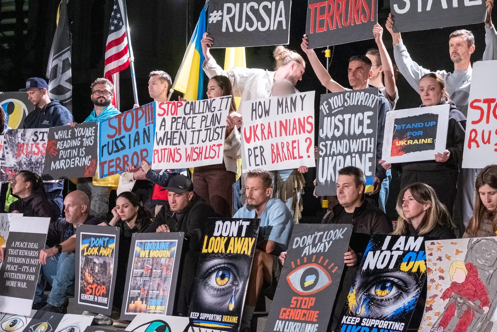 Rally participants on the Capitol steps hold signs reading "Don't look away", "Stop Russian terror" and "If you support justice, stand with Ukraine".